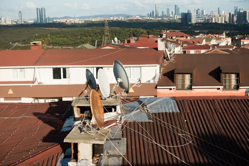 Satellite dishes on a rooftop in Istanbul, with the city's towers on the skyline behind